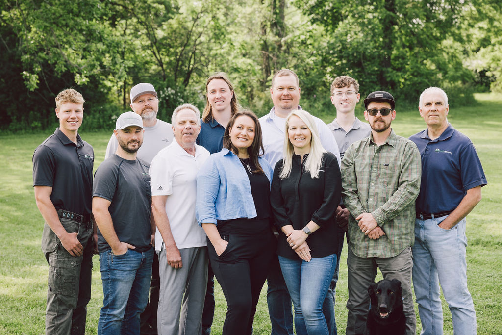 Team members gathered outdoors with a black dog